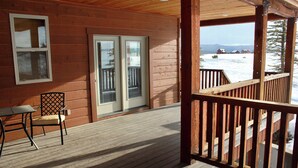Una terraza de madera con puerta de vidrio que da a un paisaje nevado.