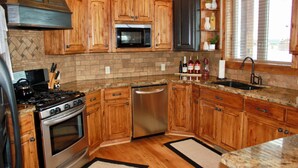 Una cocina con gabinetes de madera, estufa de acero inoxidable, microondas y lavavajillas.