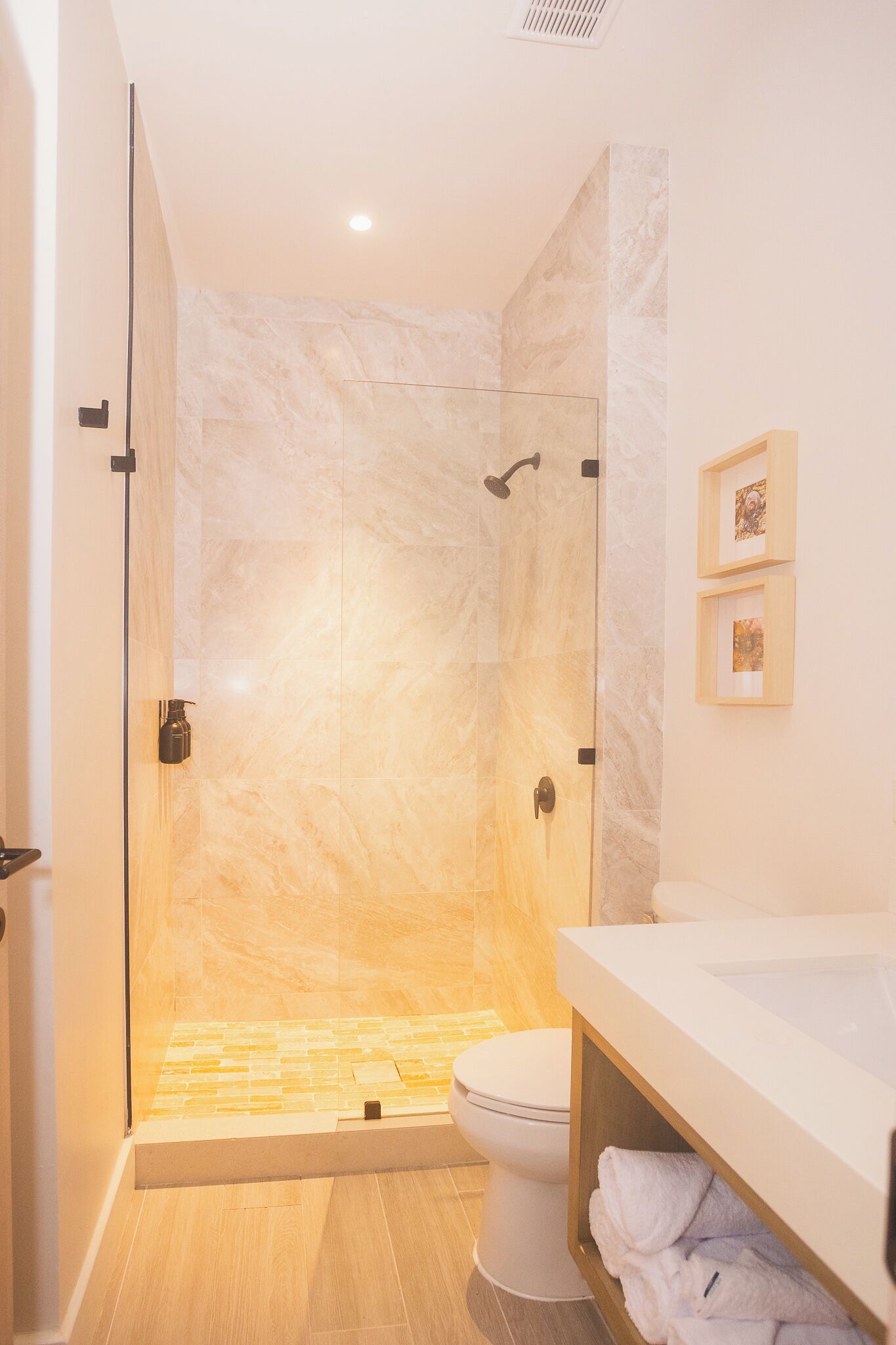 Une salle de bain moderne dotée d’une douche à parois de verre, de toilettes et d’un meuble-lavabo avec un évier.
