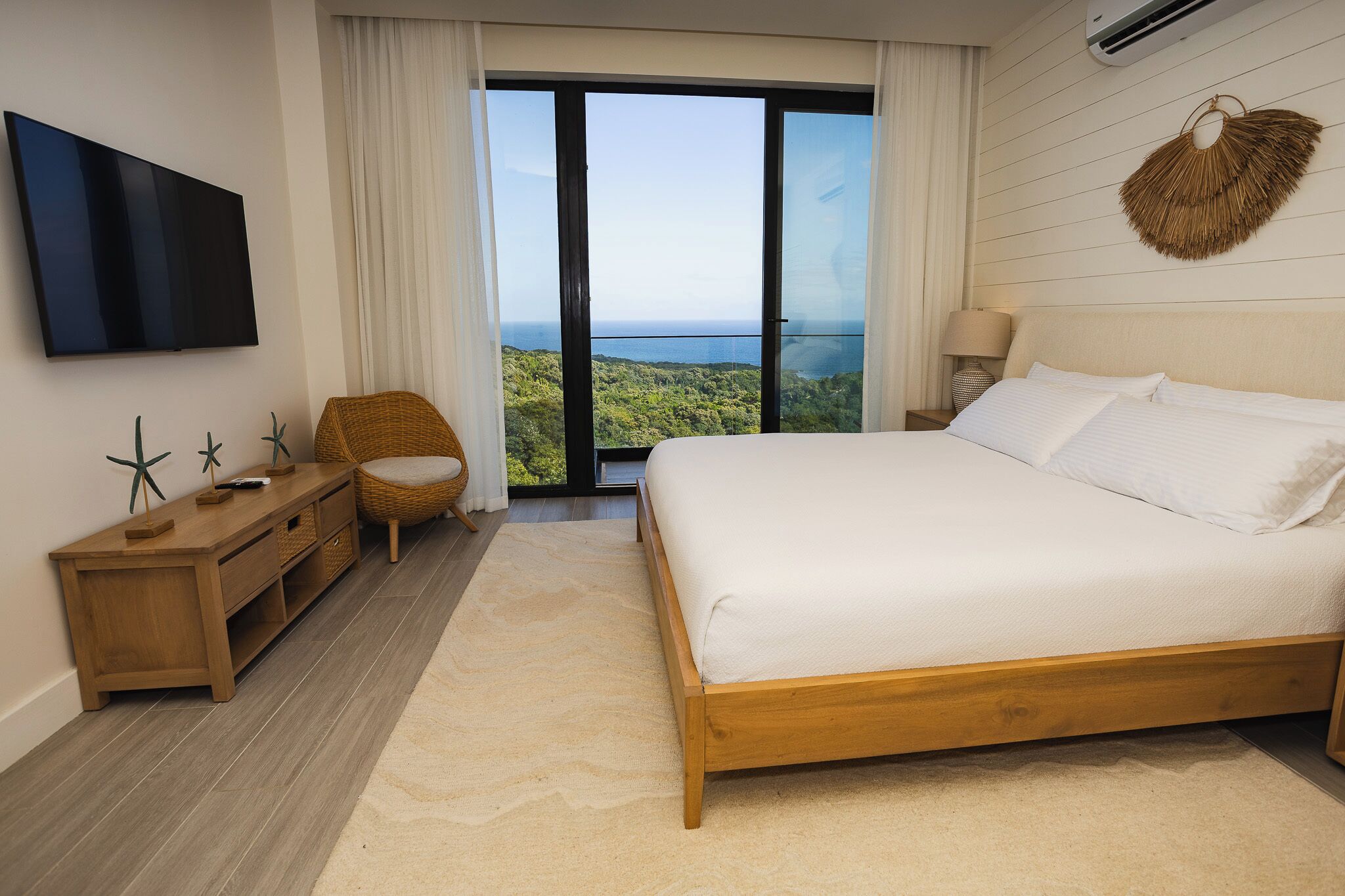 Un dormitorio con una cama grande, una mesita de noche de madera, un televisor y vistas al exterior.