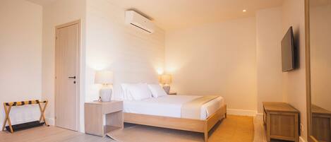 A bedroom with a bed, bedside lamps, a TV, and a wooden floor.