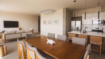 A modern kitchen with a wooden dining table, chairs, and a microwave.