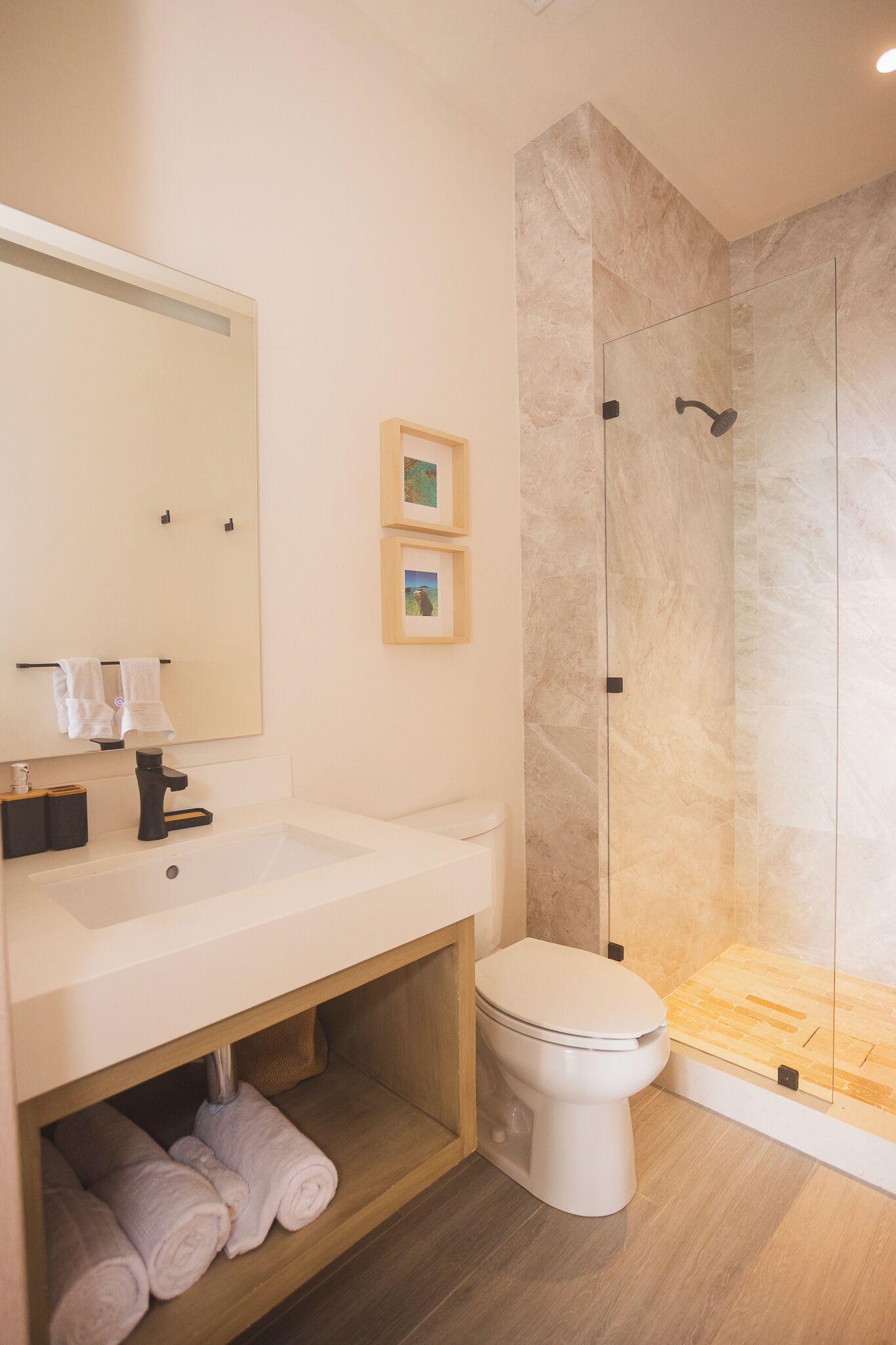 Un baño con lavamanos blanco, inodoro, espejo y cabina de ducha.