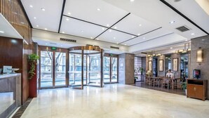 A spacious lobby with a revolving door, a reception desk, and a seating area with tables and chairs. - Homeinn Superior Yun Hotel (Beijing Qianmen) (Beijing)
