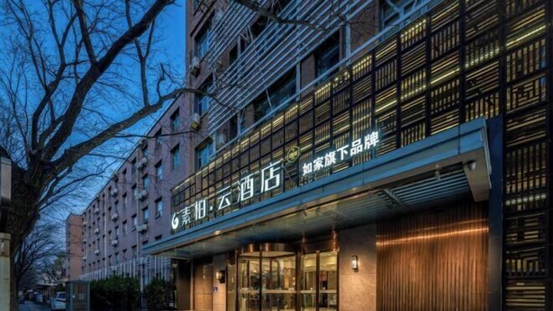 A hotel with a modern facade, featuring a prominent entrance with glass doors and a metal staircase leading up to it. - Homeinn Superior Yun Hotel (Beijing Qianmen) (Beijing)