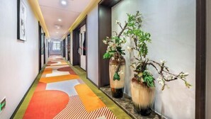 A hotel corridor with a colorful carpet, two large vases with plants, and framed pictures on the walls. - Homeinn Superior Yun Hotel (Beijing Qianmen) (Beijing)