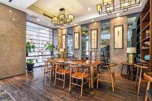A dining area with a wooden table and chairs, a chandelier, and framed pictures on the wall. - Homeinn Superior Yun Hotel (Beijing Qianmen) (Beijing)