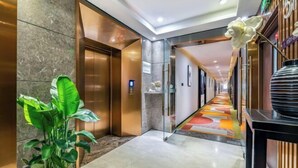 A modern hotel corridor with elevators, a patterned floor, and a potted plant. - Homeinn Superior Yun Hotel (Beijing Qianmen) (Beijing)