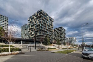 Un immeuble d’appartements moderne doté de nombreux balcons et d’un espace paysager aménagé à l’avant.