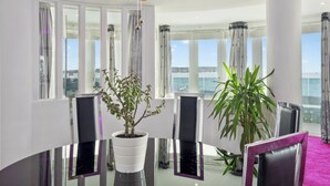 A modern dining area with a glass table, white chairs, and potted plants. - Blue Horizon (Lymington)