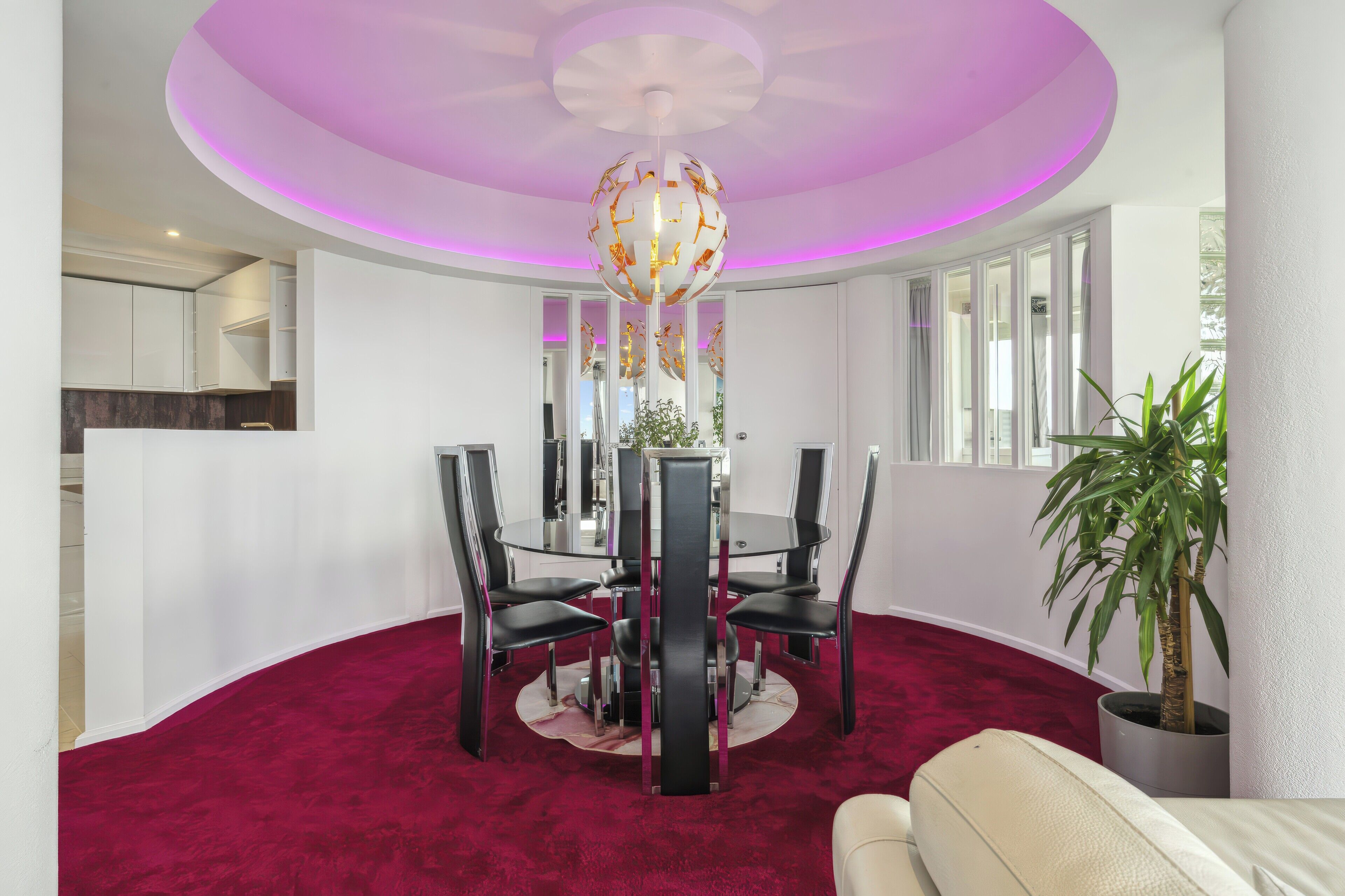 Een eetruimte met een ronde tafel, zwarte stoelen en een rood tapijt.