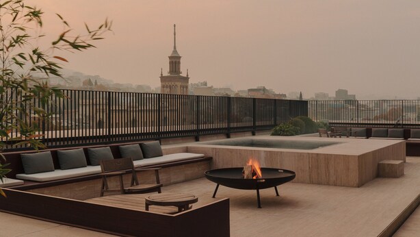 Una terrazza sul tetto con un braciere, zona salotto e vista sullo skyline della città.