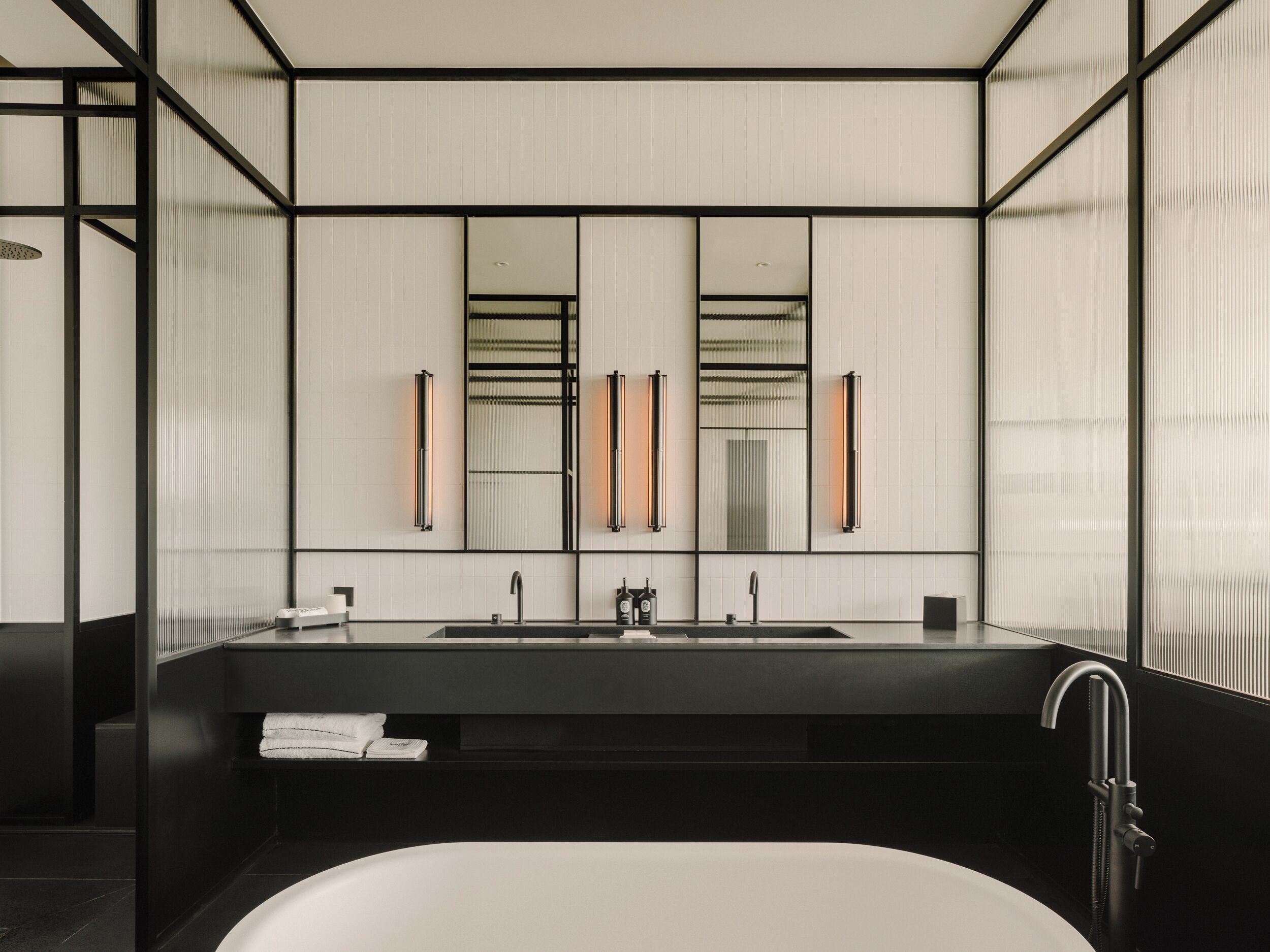 A modern bathroom with a large mirror, two sinks, and a bathtub.