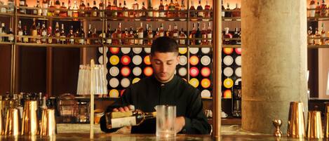 Un bar con estantes llenos de botellas de licor y un bartender preparando bebidas.