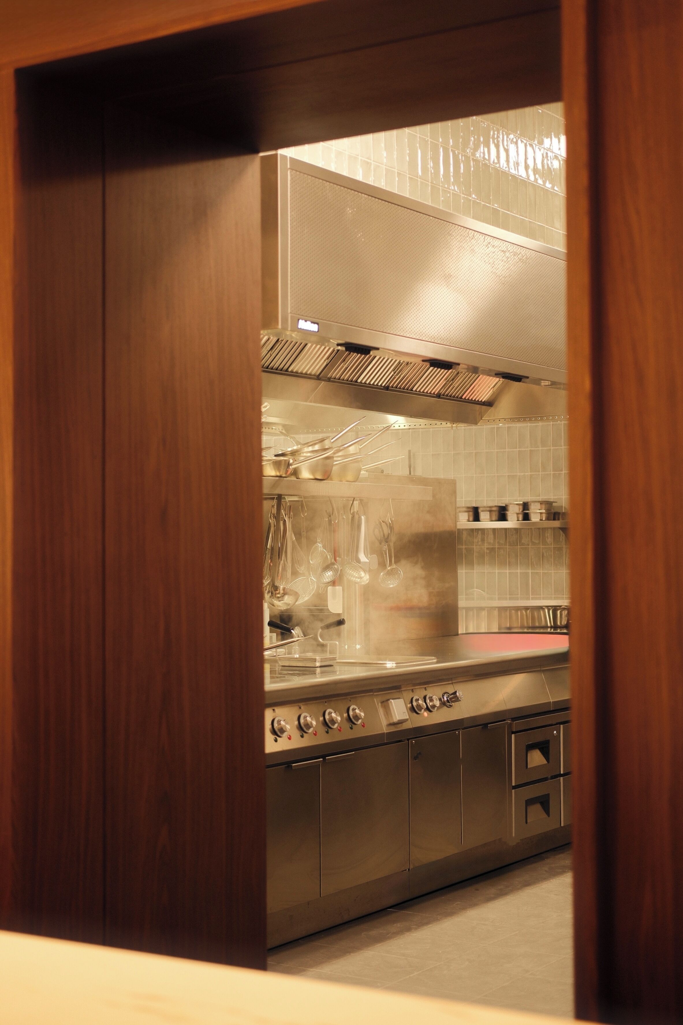 Een keuken met roestvrijstalen apparatuur, houten kastjes en een betegelde spatwand.