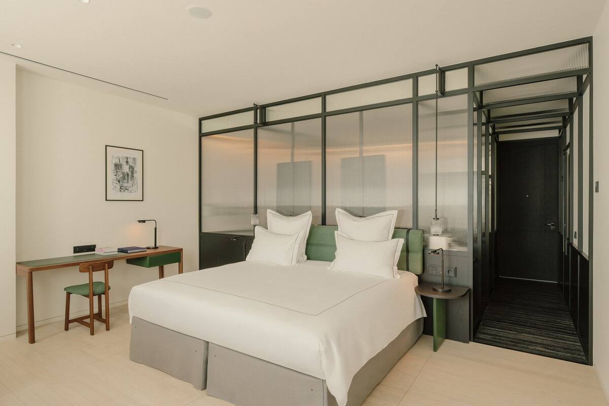 A modern hotel room with a large bed, a desk, and a walk-in closet.