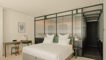 A modern hotel room with a large bed, a desk, and a walk-in closet.