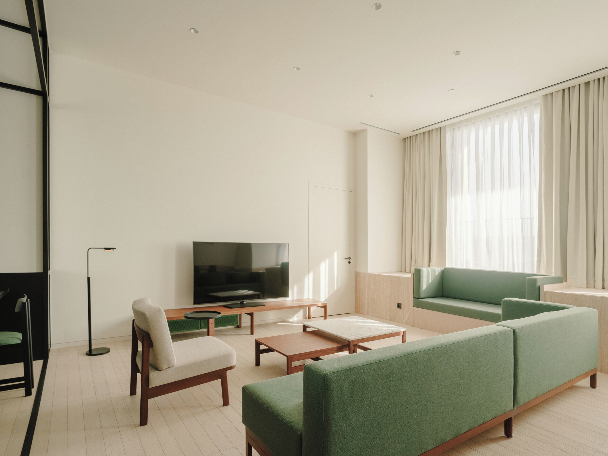 Un salon moderne avec un canapé vert, un téléviseur à écran plat et un design minimaliste.