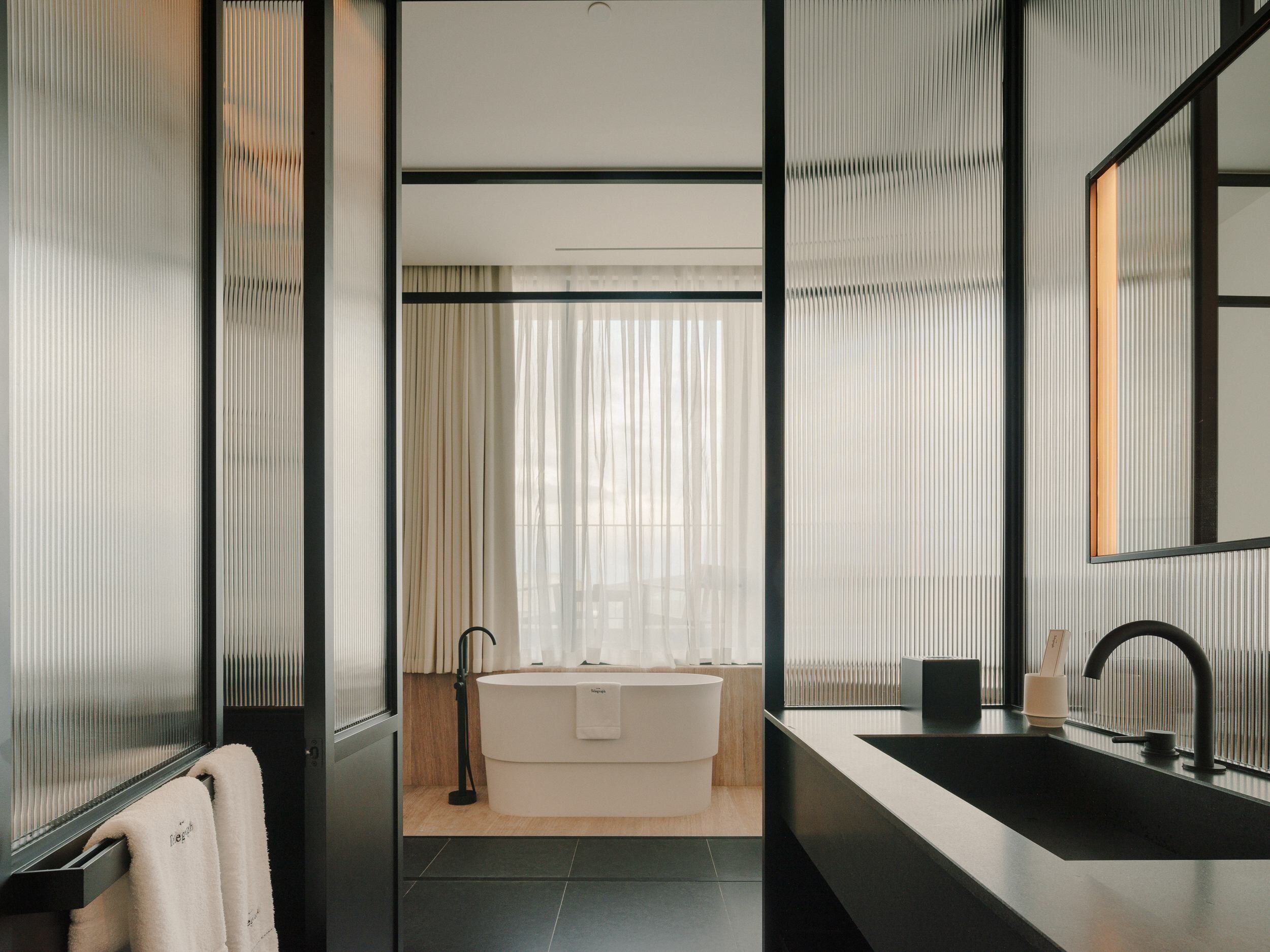 A modern bathroom with a freestanding bathtub, a large sink, and a mirror.