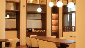 A restaurant with a long wooden table, several chairs, and hanging spherical lights.