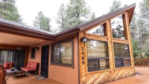 Una cabaña con fachada de madera, ventanas amplias y una terraza.