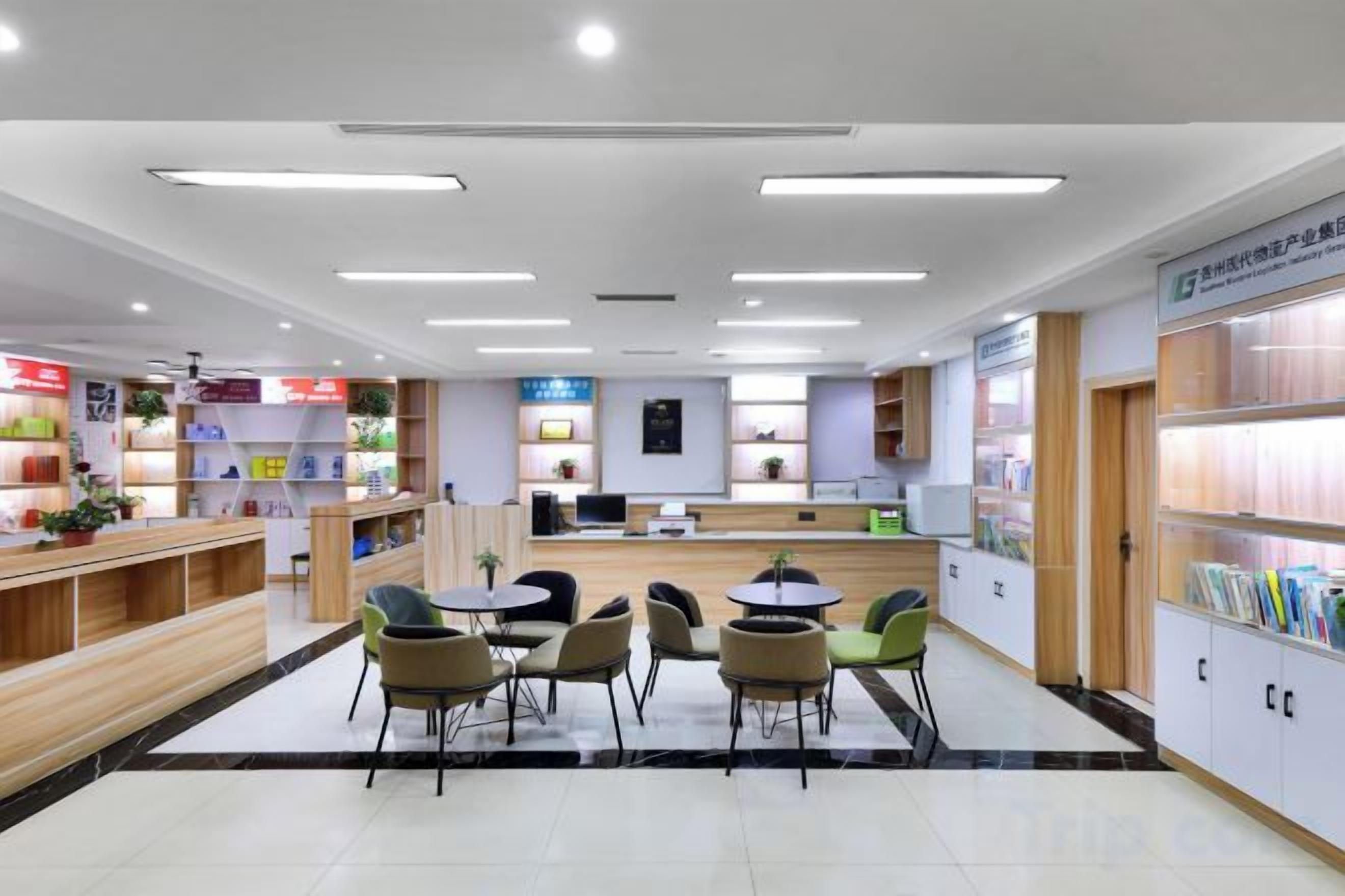 A well-lit indoor space with a reception desk, seating area, and shelves with books and magazines.