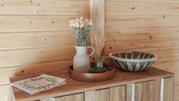 A wooden cabinet with a woven basket and a vase with dried flowers.