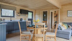 Interior de una cabaña de madera con cocina, comedor y sala de estar.