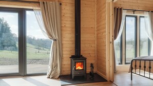 Una habitación acogedora con detalles de madera, una chimenea, ventanas amplias y vistas al exterior.