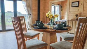 Comedor de madera con una mesa redonda dispuesta para cuatro personas, rodeada de sillas tapizadas.
