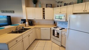 A compact kitchen with white cabinets, a dishwasher, a stove, and a refrigerator.
