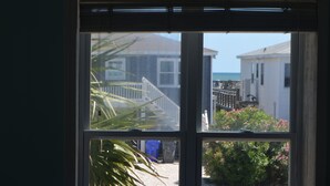 Una ventana con vista a una casa, una escalera y un cuerpo de agua.