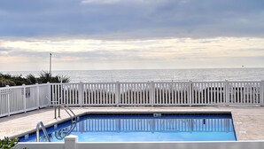 Una piscina con cerca blanca y vista al océano.