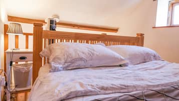 Un dormitorio con cabecera de madera, una mesita de noche con lámpara y una ventana con vistas.