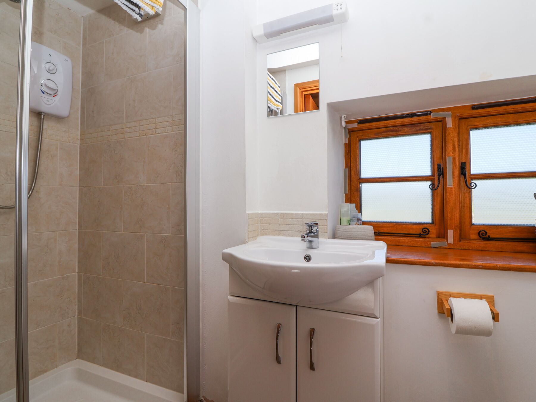 Un bagno con doccia, lavandino e finestra con vetro acidato.