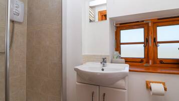 Un bagno con doccia, lavandino e finestra con vetro acidato.