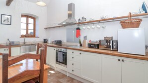 A kitchen with white cabinets, a wooden countertop, a stove, a microwave, and a refrigerator. - The Yarde Annexe (Taunton)