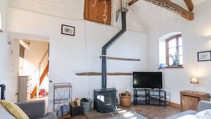 A cozy living room with a fireplace, a television, and a staircase leading to another room. - The Yarde Annexe (Taunton)