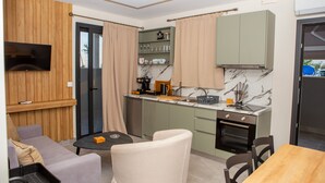 A compact kitchen with a dining area, wooden paneling, a flat-screen TV, and a coffee machine.