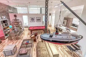 A room with a pool table, a boat, and a bar area.
