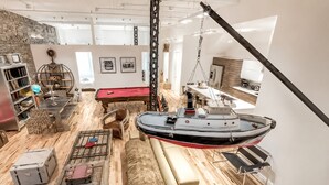 Amplia habitación con mesa de billar, un barco colgante y una estantería.