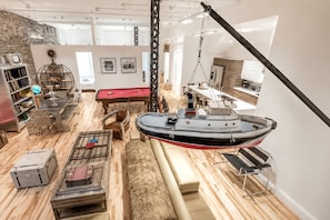 Ein geräumiger Raum mit Billardtisch, einem hängenden Boot und einem Bücherregal.