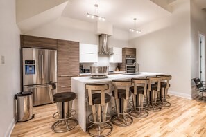 A modern kitchen with a central island, stainless steel appliances, and bar stools.