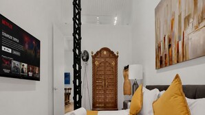 Habitación de hotel con una cama, un armario de madera, un televisor de pared mostrando una serie de Netflix y un cuadro en la pared.