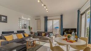 En moderne stue med sofa, skammel, spisebord og stole.