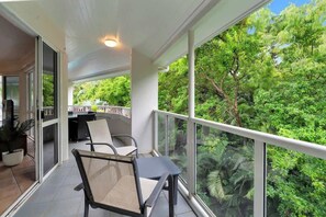 Un balcone con sedie e tavolo, affacciato su una lussureggiante foresta verde.
