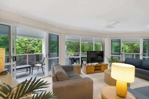Un soggiorno moderno con divano, TV e lampada, ampie finestre e un balcone.
