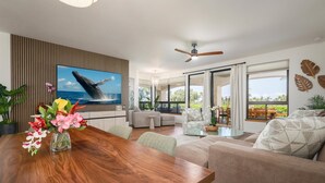A modern living room with a wooden dining table, sofas, and a large TV screen displaying a whale.