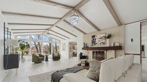 A spacious living room with a white sofa, a fireplace, and a large window. - Waterfront Paradise - 2 Lake Views in Prime Location (Battle Creek)