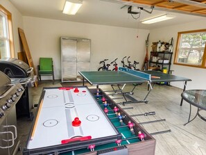 A room with an indoor foosball table, a ping pong table, and a foosball table with miniature figures.